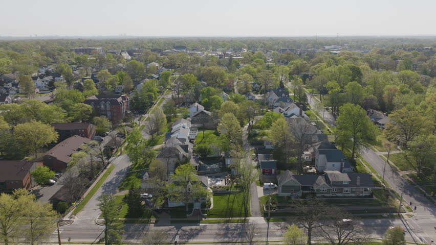 Beautiful aerial flyover of the Kirkwood neighborhood in St. Louis, Missouri, during springtime. Captures blooming trees, vibrant greenery, and charming homes. Perfect for seasonal and suburban themes