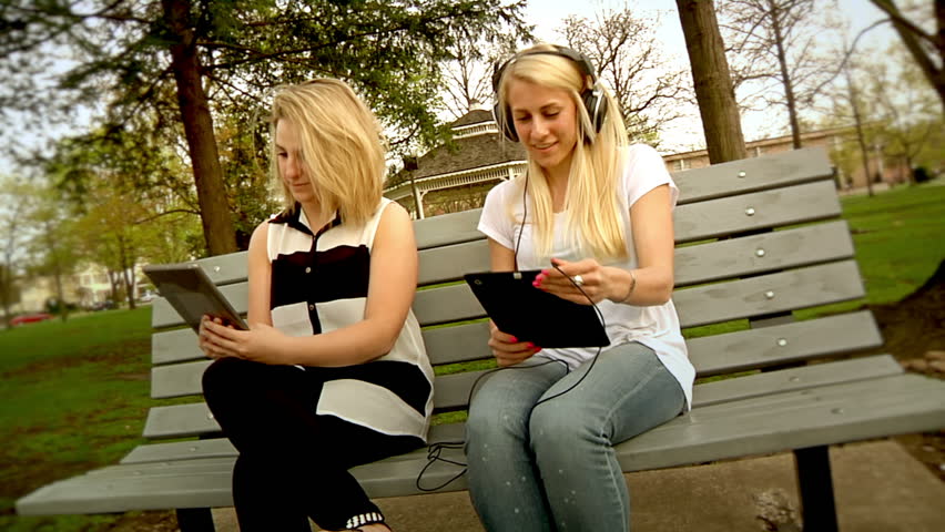 A young woman is annoyed by another woman listening to music in the park.