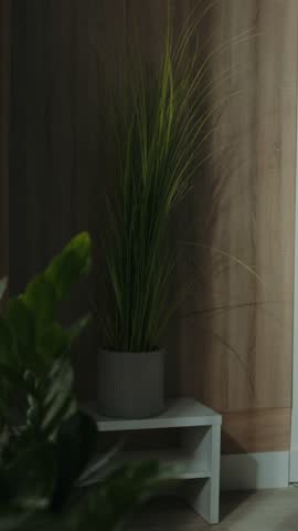 Young thoughtful beautiful woman drinking tea and looking through window while standing on windowsill at home. Footage of attractive girl tasting drink on background of modern living room. Indoors