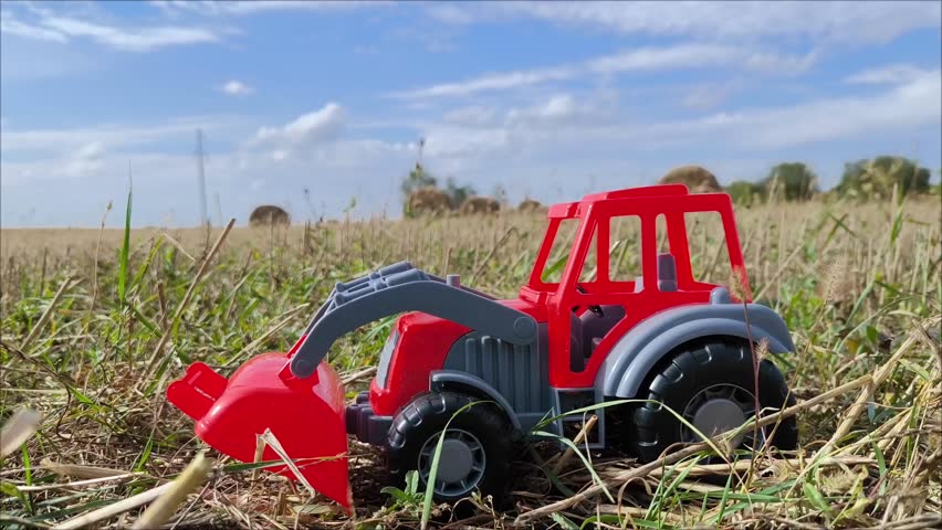 The red tractor is a toy in the field as a harvesting or sowing concept.
