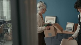 Retiring employee passing essential documents to her younger successor, taking cardboard box with her personal and work-related belongings and leaving modern office - Powered by Shutterstock - Get 15% off with code: PIKWIZARD15