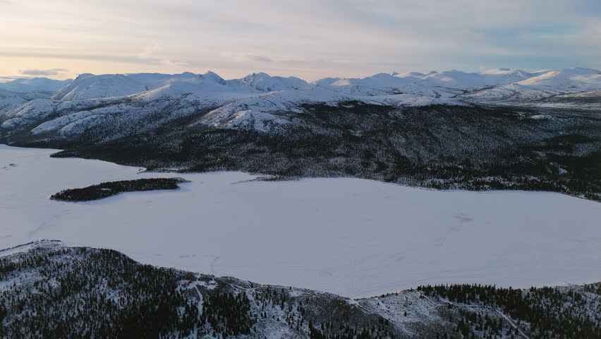 A sweeping aerial of Fish Lake in Whitehorse, Yukon, with a breathtaking view of the sub-zero Canadian wilderness blanketed in snow.