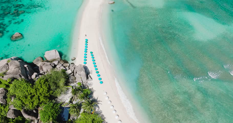 Island shoreline featuring turquoise waters, rocky formations and vibrant tropical greenery. Nangyuan Island Beach, Koh Tao, Thailand.