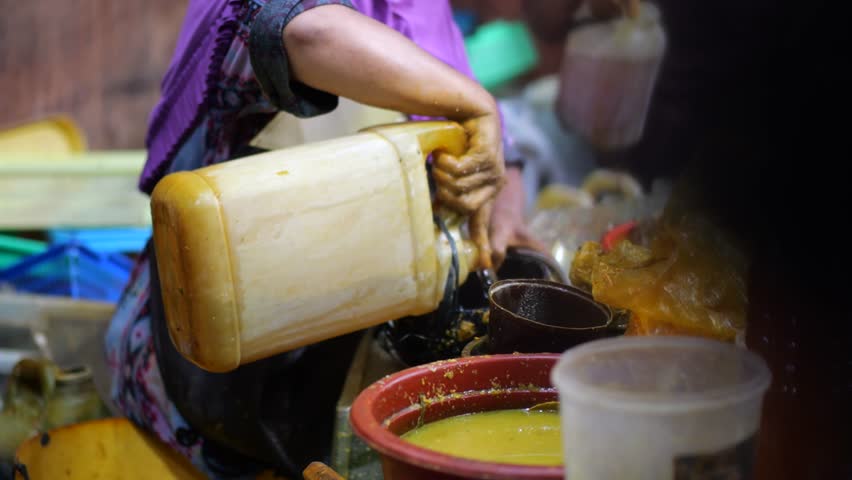 The traditional herbal medicine seller is meticulously crafting a customized herbal concoction for a customer. Using their bare hands, they expertly blend various herbal ingredients.
