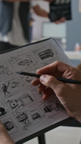 Vertical shot of unrecognizable hand drawing storyboard, working on set in professional video production studio