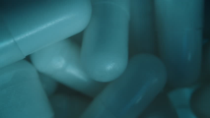 Close Up of White Capsules Inside a Blue Jar as the Camera Slides Upwards Highlighting Their Glossy Surface and Even Distribution Wellness and Healthcare