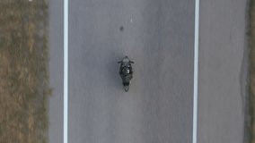 Top view to biker driving motorbike during road trip. Man ride fast on modern sport motorcycle at highway. Motorcyclist racing his bike on country road. Concept of journey and adventure. Aerial shot - Powered by Shutterstock - Get 15% off with code: PIKWIZARD15