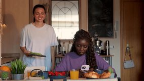 Multiracial women sharing breakfast moment, enjoying fresh croissants, strawberries, juice while laughing together in bright kitchen space - Powered by Shutterstock - Get 15% off with code: PIKWIZARD15