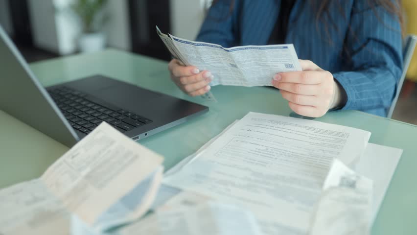 Close-up of a woman handling cash and paperwork while paying bills at a home desk. A scene depicting financial management, budgeting, and bill payment.