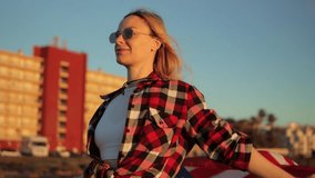 Patriotic young woman waving american flag, wearing sunglasses and  hat against urban sunset cityscape, embodying summer freedom.Usa celebrate 4th july. Independence day concept - Powered by Shutterstock - Get 15% off with code: PIKWIZARD15