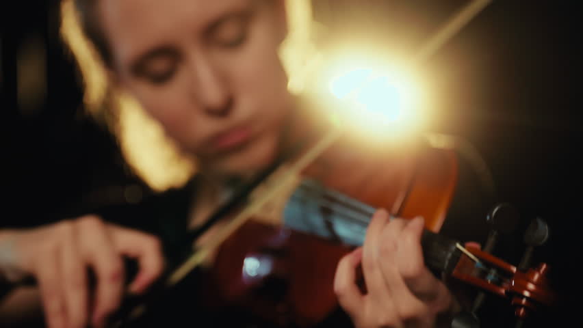 Cinematic closeup portrait of beautiful violinist woman performing music in rain . Self-expression and express emotions and feelings, romantic love song, pretty caucasian lady playing violin, solo