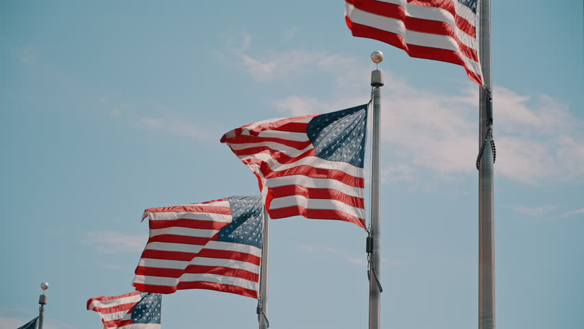 Multiple American Flags Waving Against Blue Sky