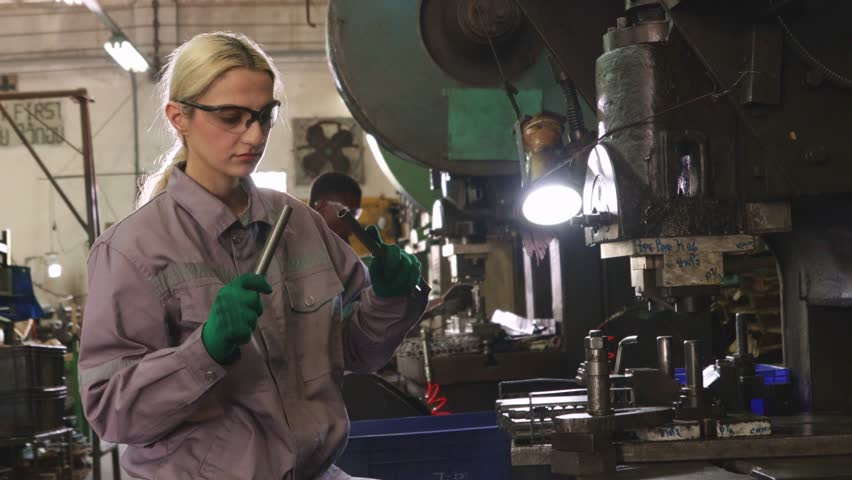 Female factory mechanics inspecting sheet metal stamping work in a factory in the automotive parts manufacturing industry, turning and metal stamping.