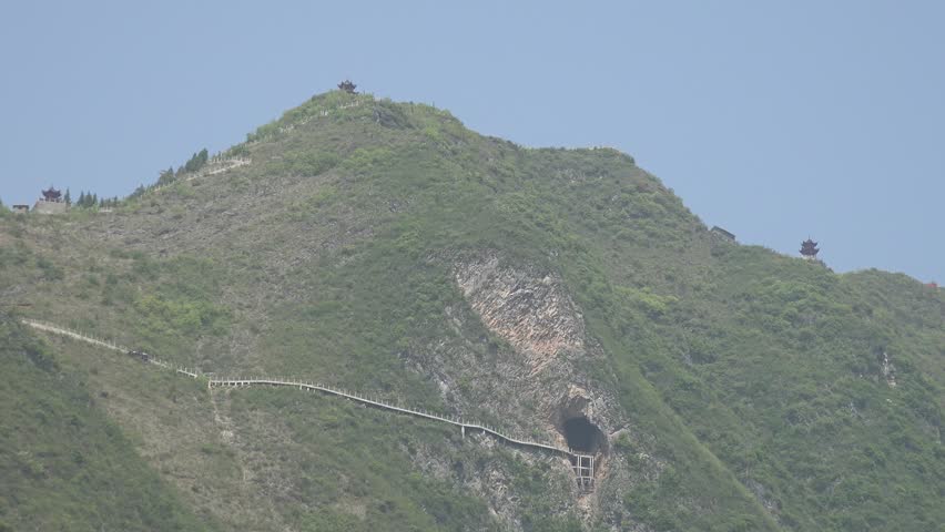 A long flight of stone stairs winds up a green hillside, just visible far across the landscape.