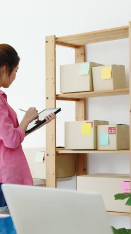 Vertical Screen : Young Asia entrepreneur businesswoman check product purchase order on stock and save to tablet computer work at home office. Small business owner, online market delivery concept.