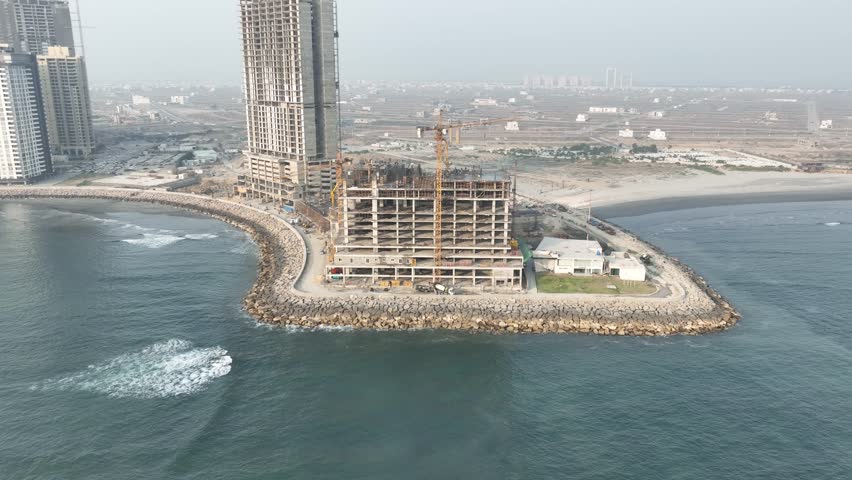 Aerial view of a building under construction in Karachi, Pakistan, with cranes and other construction equipment visible