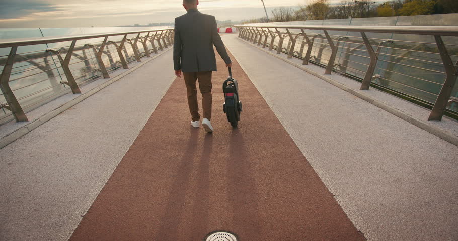 Senior Man Riding Electric Mono Wheel Gyro Scooter Personal Electrical Transport City Street Outdoors. People Ecological Electric Transportation Vehicle Self-Balancing Monowheel.