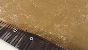 Brown murky water next to sunlit wooden deck with metal fixtures and strong textures - Powered by Shutterstock - Get 15% off with code: PIKWIZARD15