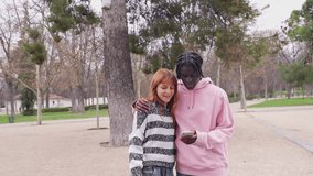 Interracial couple sharing joyful moment while browsing smartphone screen during park walk, radiating connection and happiness together - Powered by Shutterstock - Get 15% off with code: PIKWIZARD15