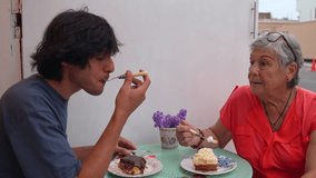 Grandson and grandmother share a pleasant moment, eating dessert and chatting at a table with purple flowers - Powered by Shutterstock - Get 15% off with code: PIKWIZARD15