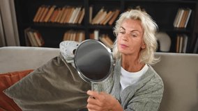 Love yourself. Beautiful old mature woman enjoying mirror reflection. Senior adult older lady looking at mirror confident happy on sofa at home. Woman doing daily morning beauty routine. Self love - Powered by Shutterstock - Get 15% off with code: PIKWIZARD15