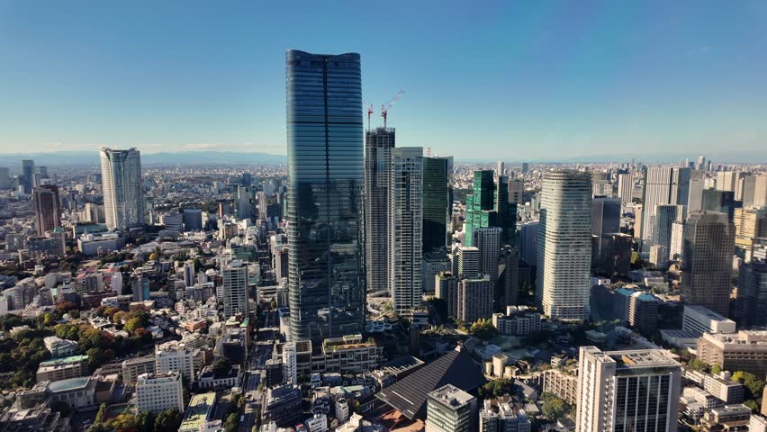 Modern skyscrapers rising above Tokyo cityscape in Minato ward with Azabudai Hills, featuring Mori JP Tower, under a clear blue sky