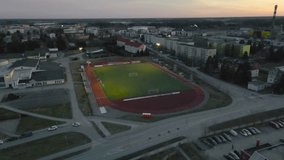 Aerial high view of Laagri, Estonia sports stadium at dusk evening sunset sky. Ascending view of soccer green turf field illuminated by stadium lights. Scenic empty football field with urban landscape - Powered by Shutterstock - Get 15% off with code: PIKWIZARD15