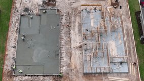 Aerial view of newly poured concrete slab next to home that is being constructed with wooden framework in Georgetown Texas - Powered by Shutterstock - Get 15% off with code: PIKWIZARD15