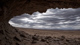 A breathtaking view from within a cave, featuring a dramatic sky and expansive desert landscape surrounding it - Powered by Shutterstock - Get 15% off with code: PIKWIZARD15