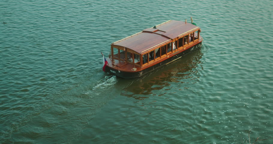 Vintage wooden tour boat with the name Praha glides through Vlata river in Prague during golden hour