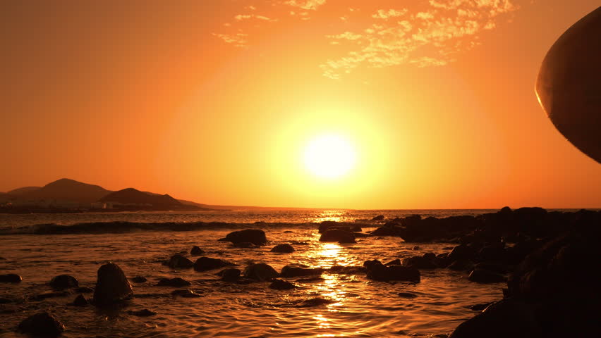 SILHOUETTE, LENS FLARE: Lady with a surfboard crosses the shoal as she walks towards breaking waves in golden light. Surfer in bikini goes into water to catch some evening waves at Lanzarote island.