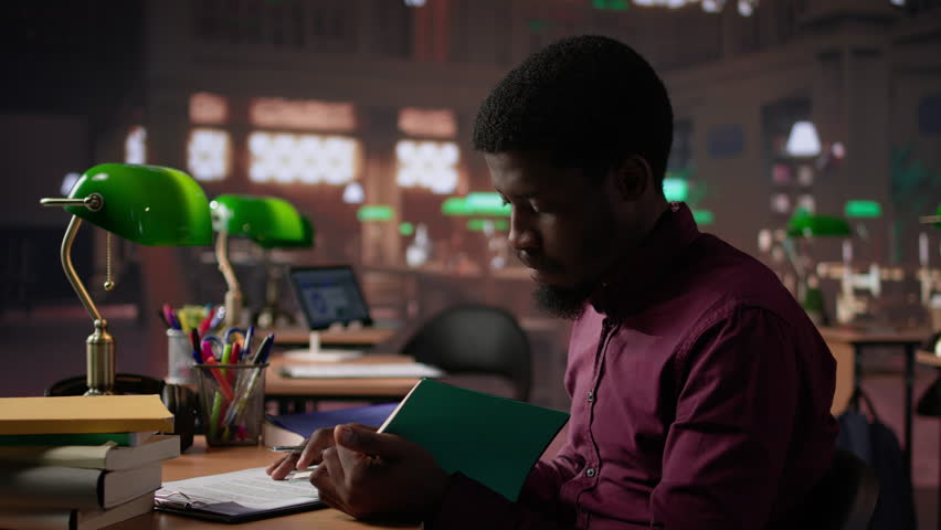 African american guy studies for a critical law exam and reading specialty books to complete class notes with reliable academic information. Studying in the library before the test. Camera B. - Powered by Shutterstock - Get 15% off with code: PIKWIZARD15