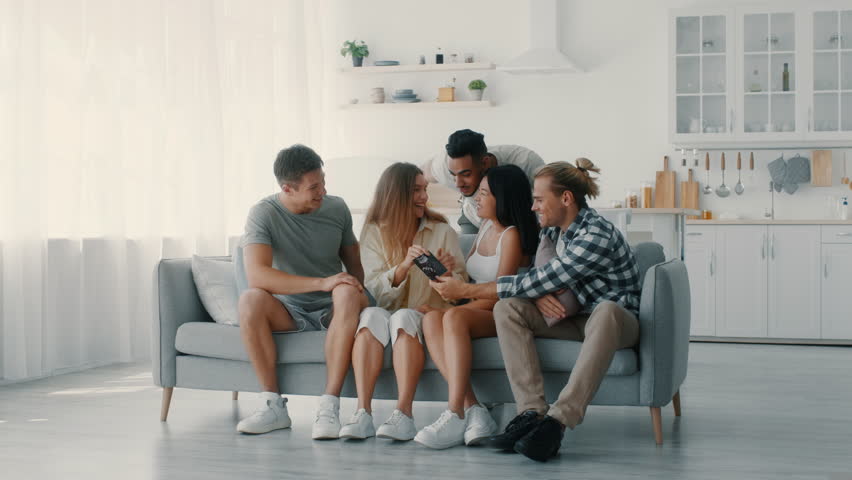 A group of diverse friends shares laughter and stories in a cozy living room. They engage in fun activities, creating joyful moments together in a bright, inviting atmosphere.