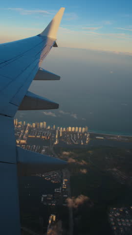 Vertical Screen: The breathtaking view from an airplane window during flight beautifully captures the sky and clouds at sunset. The airplane is gracefully taking off into the evening sky