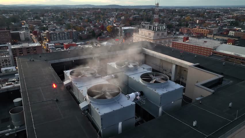 Aerial orbit shot of rotating propeller of Air Conditioner on top of tower in Lancaster City at sunset. Pennsylvania, America