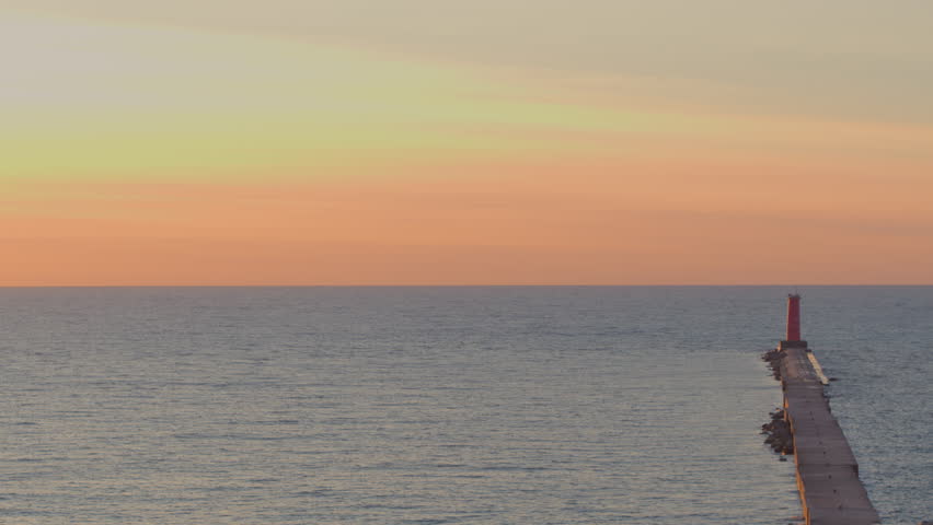 Stunning aerial view of a serene Lake Michigan sunrise with an ombre sky and the Sheboygan lighthouse with calm water, peaceful morning light, and vibrant colors. Perfect for travel and nature themes.