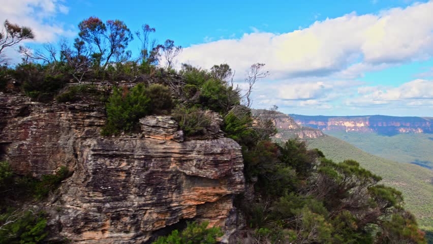 A breathtaking aerial view of Blue Mountains National Park showcases dramatic cliffs and valleys blanketed in eucalyptus forests. Australia's iconic wilderness in golden sunlight.