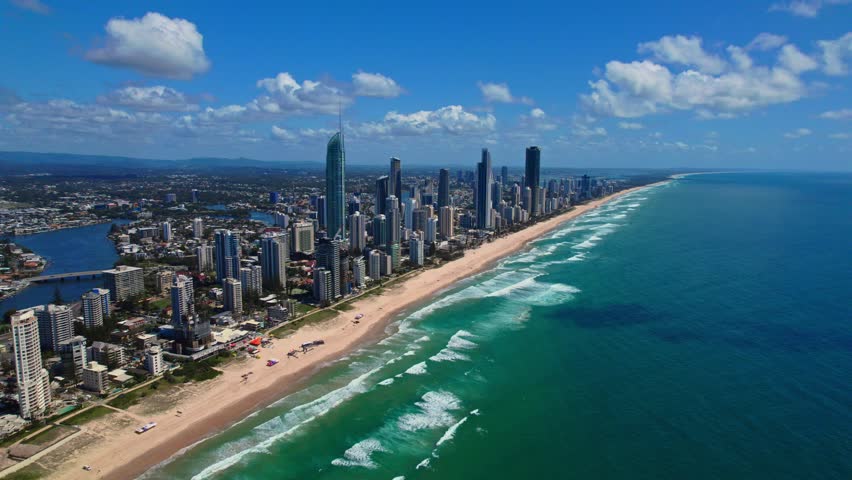 Breathtaking aerial footage of Gold Coast showcasing coastal skyscrapers, endless sandy beaches, ocean waves, and blue skies. Vibrant summer day highlights this luxurious resort city.