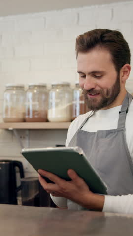 Coffee shop, barista and man with tablet for online sales, order update or check inventory. Digital technology, cafe and waiter on internet for customer reviews, stock or discussion for planning menu