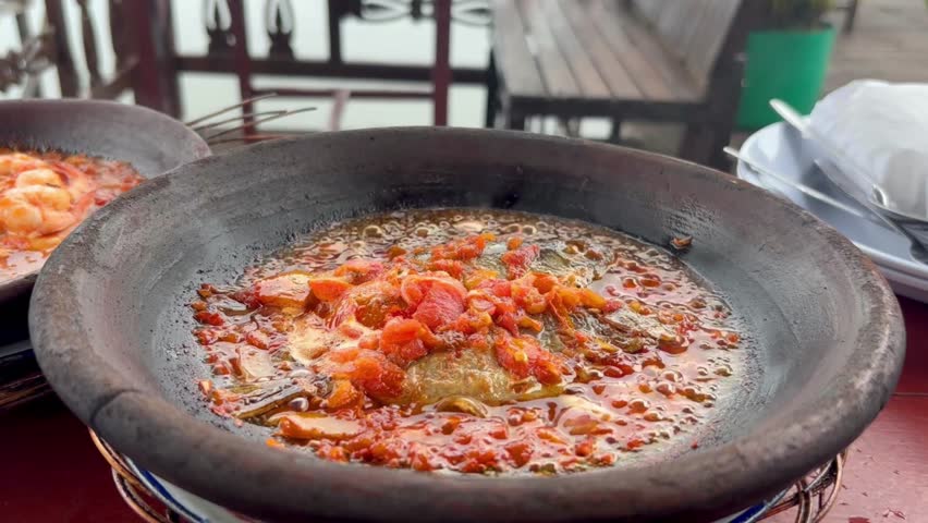 Pan-seared shrimp in spicy sambal served sizzling hot in a traditional clay mortar. Indonesian seafood dish called Gammi Udang