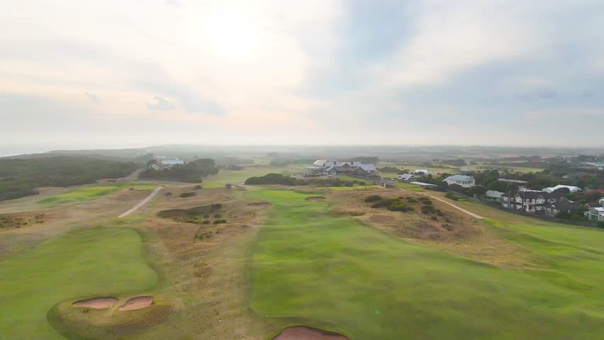 Drone footage captures the expansive greens and coastal landscape of Barwon Heads Golf Course under soft morning light