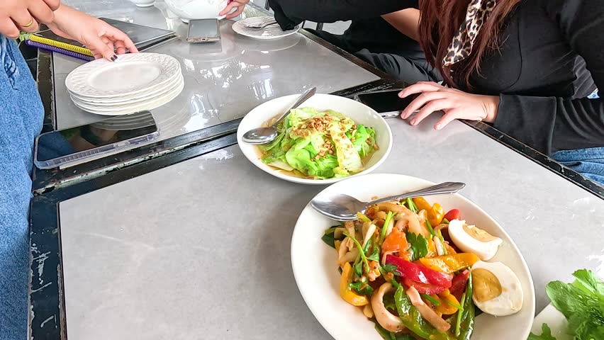 A table set with vibrant Laotian dishes, including fresh vegetables and grilled meats, in a casual outdoor setting