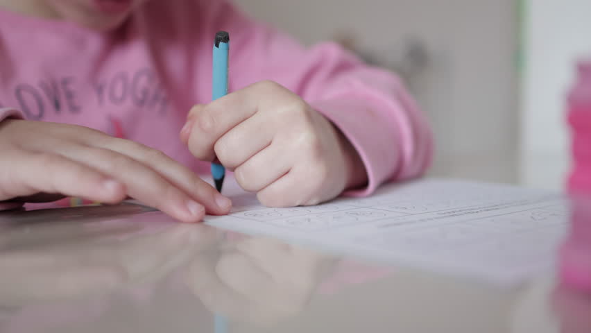 Little girl writing with pencil — focused hand detail. clousep shot