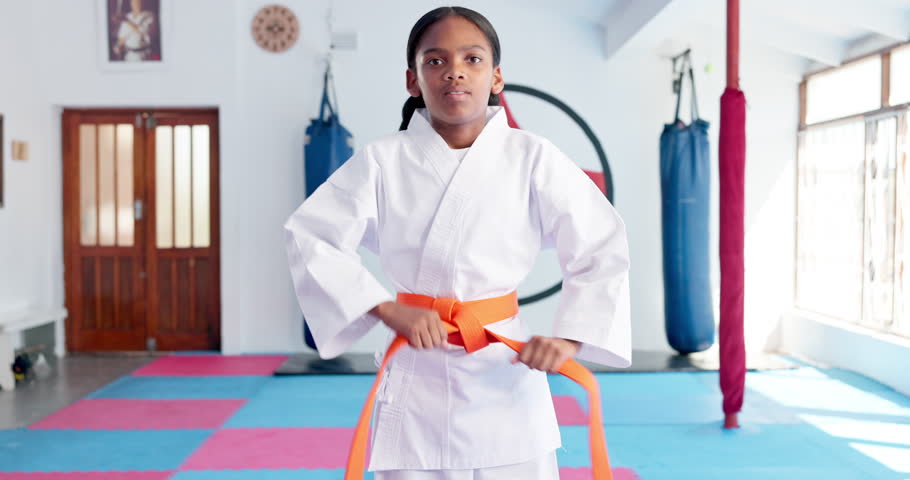 Girl, karate and ready with orange belt for martial arts training, self defense or fighting competition. Portrait, teenager or fighter preparation with strap or fist for taekwondo challenge in dojo