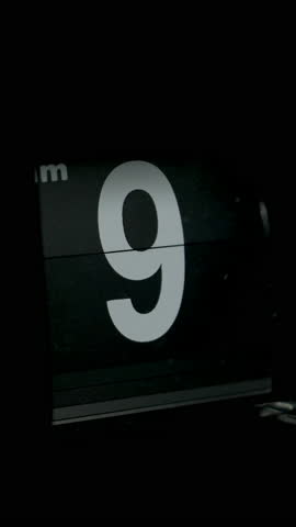 Flipping clock on a black background, in the style of time-lapse video.