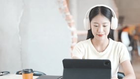 Young asian student wearing wireless headphones, studying online through tablet during classroom learning session with focused, cheerful expression - Powered by Shutterstock - Get 15% off with code: PIKWIZARD15
