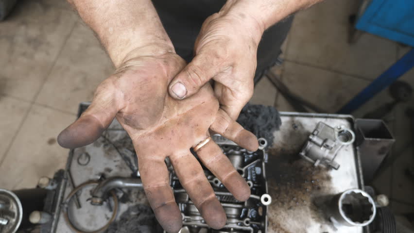 POV male dirty hands of young mechanic at workshop. Repairman rubbing unclean arms from fuel oil after hard work at garage. Concept of maintenance service. Slow motion