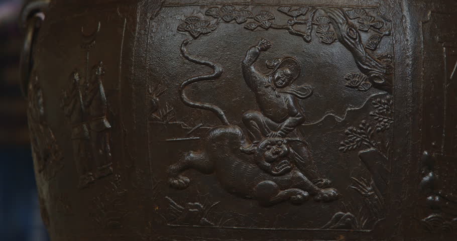 Chengdu, Sichuan, China. Ornate Iron Pot And Liu Bei Statue In Mausoleum Of Liu Bei, Wuhou Memorial, Three Kingdoms Temple. Depicts Scene Of Fighting With Tiger. Engraving On Bronze Incense Burial Pot