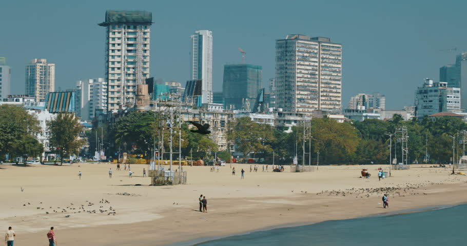 Mumbai, India. Pigeon Fly In Slow Motion Above Around Back Bay Coast Of Mumbai City. City Skyline From Marine Drive. Skyscrapers And Saifee Hospital. Clear Blue Sky. Many Ships And Boats Drift In
