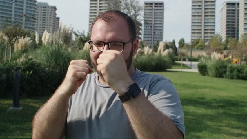 Man in glasses with extra weight boxing in public park to give fight to sugar and overeating and finally have strong body